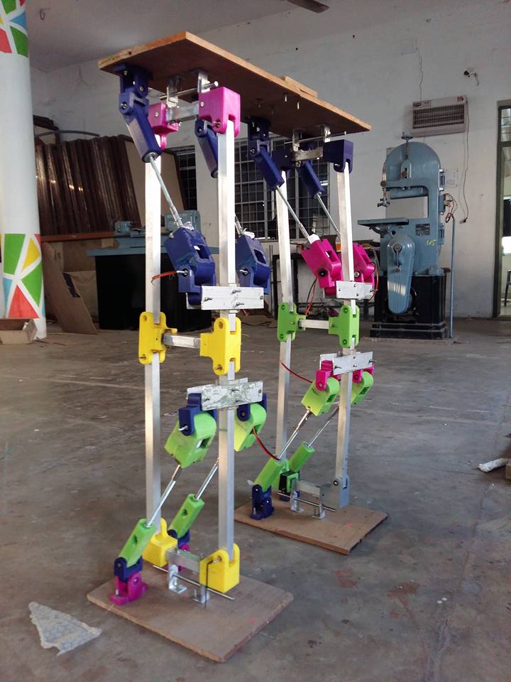 Two humanoid leg mechanisms standing in a college workshop